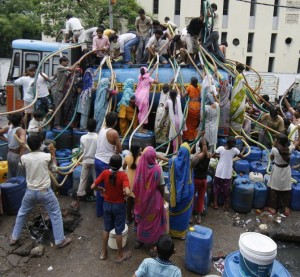Residents of Sanjay Colony, a residential neighbourhood, crowd around a water tanker provided by the state-run Delhi Jal (water) Board to fill their containers in New Delhi June 30, 2009. Delhi Chief Minister Sheila Dikshit has given directives to tackle the burgeoning water crisis caused by uneven distribution of water in the city according to local media. The board is responsible for supplying water in the capital. REUTERS/Adnan Abidi (INDIA SOCIETY) - RTR256UB
